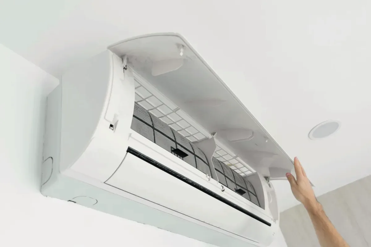 Hand opening the cover of a wall-mounted ductless air conditioner